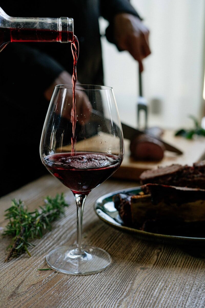 Verre de vin rouge tenu en main pour observer la robe